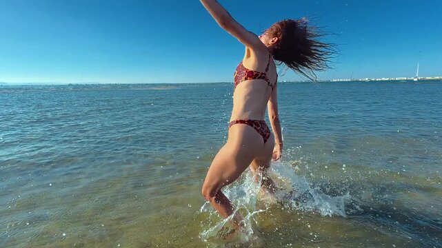 A girl runs across the sea and does a somersault, enjoying the rest and freedom
