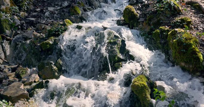 Cascade waterfall falling on rocks in spring forest