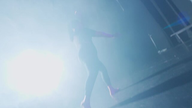 Shot from a dynamic low angle, an expressive dancer steps forward into a bright stage light. Her fluid, upward movements signify hope, liberation, and breaking the chains of emotional abuse.