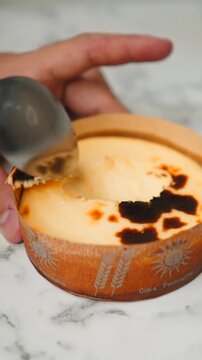 Person scooping a delicious burnt basque cheesecake with a spoon