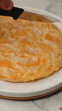 Spanish omelette with potato and onion being cut with a knife on a plate