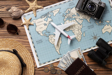 Travel accessories on wooden table with world map, airplane, passport, and money © MST