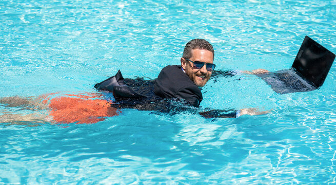 Funny crazy businessman rest in formal wear in pool. Crazy summer. Fun business lifestyle. Businessman in suit with laptop in swimming pool. Crazy business man on summer vacation. Remote working job