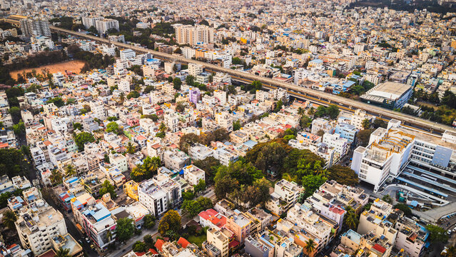 Aerial view of Bangalore city, Karnataka, India, showing a vast urban landscape with dense residential neighborhoods, modern development, and a lake surrounded by the expanding metropolis.