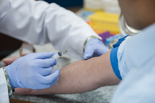 Young doctors and medical technician performing blood draw in clinical laboratory setting