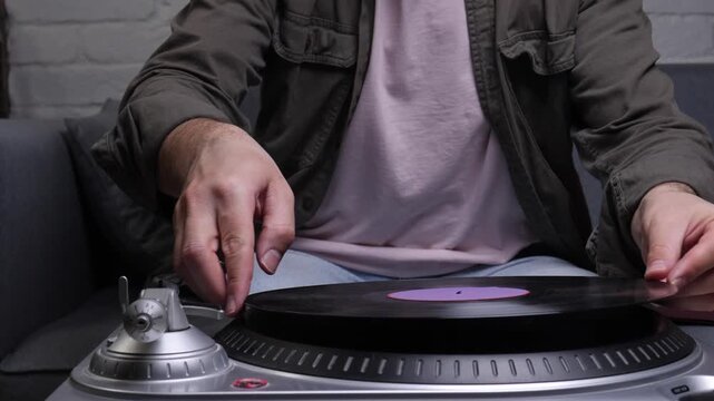 Hands gently placing a black vinyl record with a purple label onto a modern turntable, setting the tone for analog listening and relaxed home hi fi music enjoyment