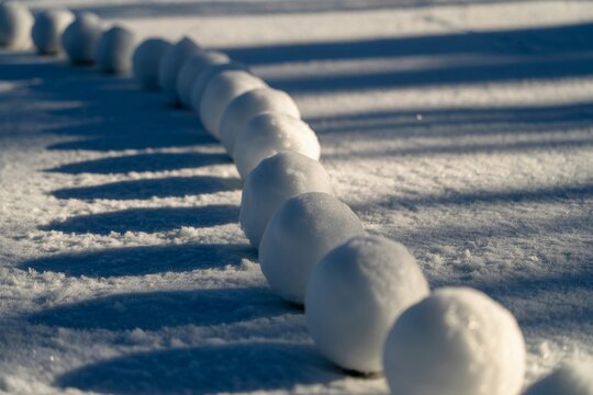Row of snowballs lined up in a snowy field on a sunny winter day
