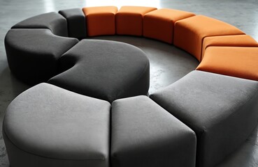 Fototapeta premium Curved modern modular seating in grey black and orange hues. Textured fabric upholstery forms a smooth sleek geometric shape. Arrangement for comfort in lounge interior decor.