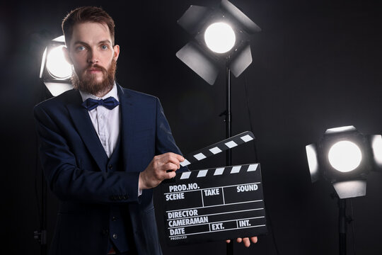 Professional actor in suit with clapperboard on stage