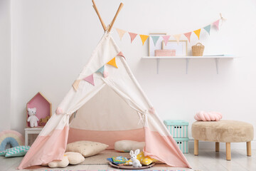 Cute wigwam with pillows, books and toys in stylish child's room. Space for text © New Africa
