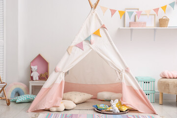 Cute wigwam with pillows, books and toys in stylish child's room © New Africa