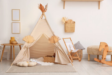 Stylish wigwam with dry leaves in child's room © New Africa