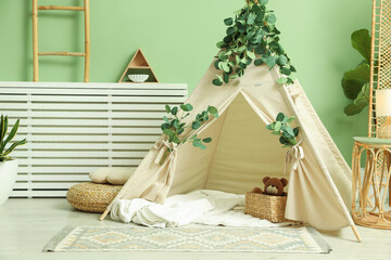 Cute wigwam with leaves and blanket in stylish child's room. Space for text © New Africa