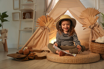 Little girl with drawing of map near wigwam at home. Space for text © New Africa
