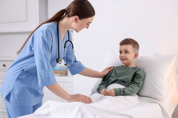 Fototapeta premium Doctor examining little child on bed in hospital