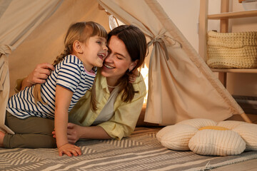Mother and her daughter in toy wigwam at home © New Africa