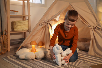 Little boy playing with toys near wigwam at home © New Africa