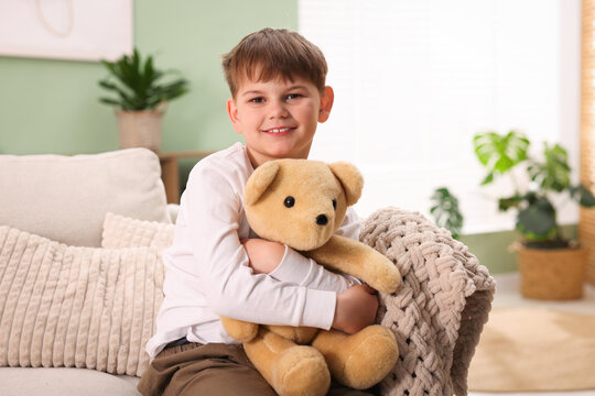 Little boy with his teddy bear on sofa at home