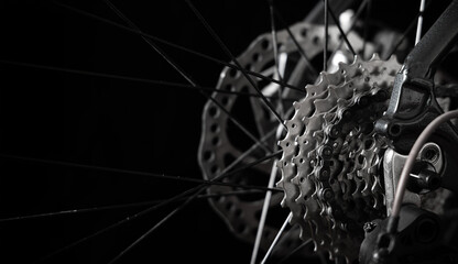 Close-up of bicycle rear cassette and chain with visible spokes on black background. Concept of cycling, sport, mechanical engineering, maintenance, repair and performance. © Valentin Kundeus