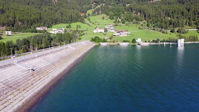 Aerial drone view of Resia Lake dam: sustainable hydroelectric power infrastructure, Renewable energy production, and environmental engineering in the Italian Alps landscape