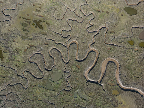 Aerial view of tidal channels and salt marsh patterns at Burnham Overy Staithe, Norfolk, England, UK. Natural coastal textures, winding waterways and abstract organic shapes