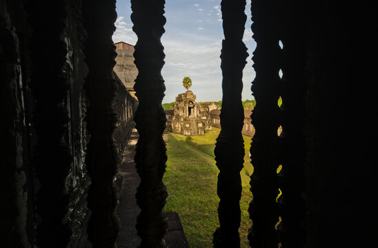 Dark temple interior at Angkor with backlit carved stone balusters creating striking silhouette patterns, Cambodia.