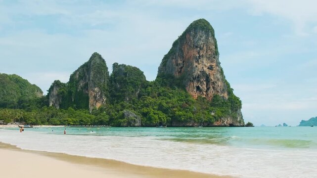 Scenic view of Railay Beach with limestone karst cliffs, sand and turquoise sea in Krabi province, Thailand. Calm tropical shoreline and rock formations. Travel destination, nature and tourism concept