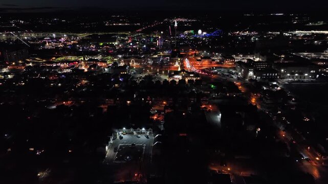 Aerial night approach to small town in winter with festive Christmas lights, glowing streets and traffic. Vibrant holiday atmosphere in American cityscape. Wide shot. Hershey, Pa downtown.