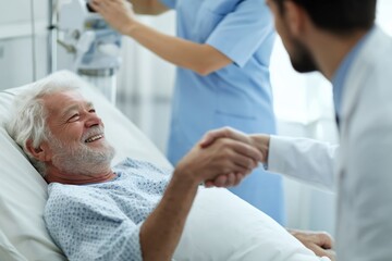 Fototapeta premium Smiling Senior Patient Shaking Hands with His Doctor in the Hospital