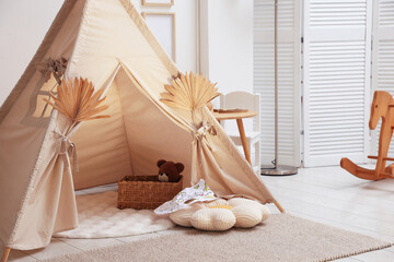 Stylish wigwam with dry leaves in child's room. Space for text © New Africa