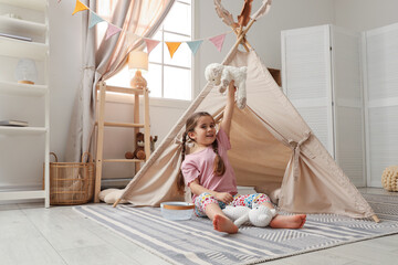Little girl playing with toys near toy wigwam in playroom © New Africa