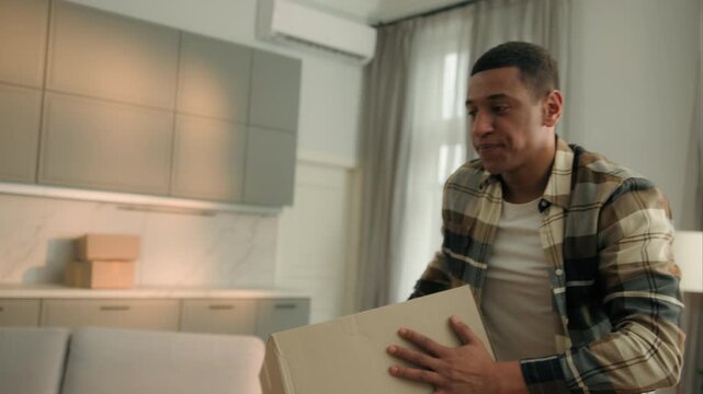 African American man with many boxes crash into couch sofa falling drop parcels ethnic male guy carry heavy goods buying stuff for new home flat disappointed worried internet shopping moving orders
