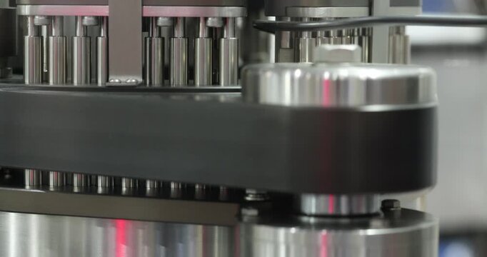 Close up of rotating multi head mechanism with metal pins moving in circular motion. Automated industrial system for precise processing, filling or assembly in modern factory environment.