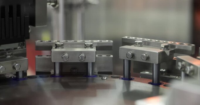 Close up of rotating multi head mechanism with metal pins moving in circular motion. Automated industrial system for precise processing, filling or assembly in modern factory environment.