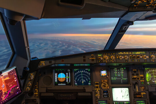 Airplane cockpit view above clouds at sunset with instruments