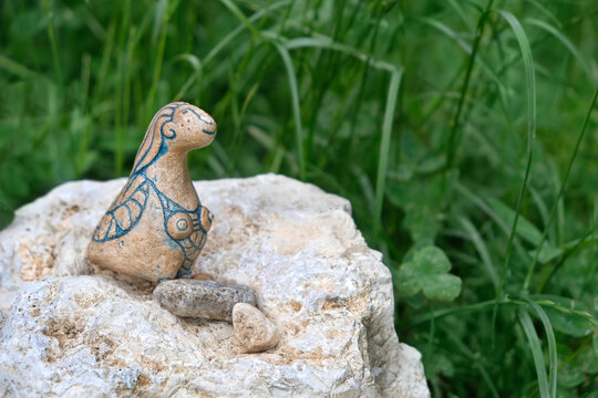 Stone figurine of mythological women bird creature on nature background. magical creature with head and breasts of woman but body of birds. Siren pagan greek or slavic mythology spirit Alkonost bird