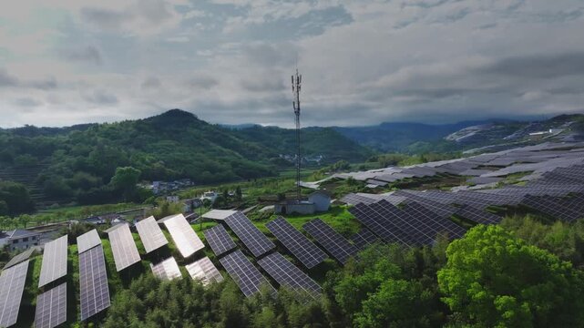 Mountainous photovoltaic power station coexisting with telecommunications tower under cloudy sky