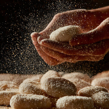 Macro shot of Korean rice cakes (tteok) being stretched and pulled by hands dusted with roasted soybean powder, extreme close-up showing the elastic texture and fine powder particles catching the ligh