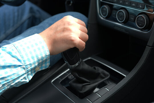 Hand shifting manual gear stick in car close up driver control