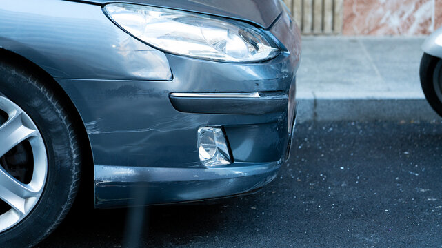 Scratched car bumper and headlight damage close up vehicle