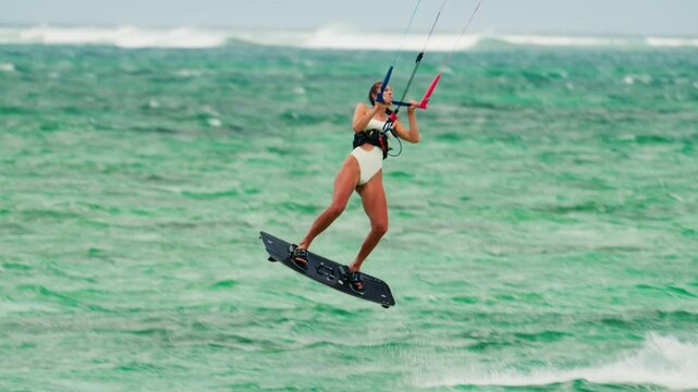 Sports woman kitesurfing in ocean in white bikini. Extreme summer sports