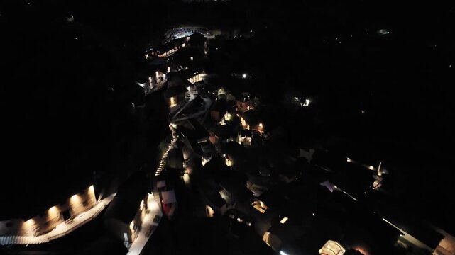 Nighttime aerial view of a historic town with winding illuminated alleys and traditional architecture