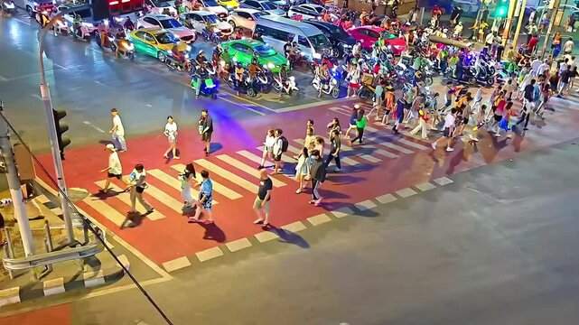 Cars and Motorcycle traffic with walking pedestrian on road intersection crosswalk, Nighttime Downtown, Urban Commute, Bustling City, Aerial Shot, Timelapse