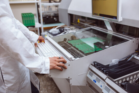 Factory of electronic products. The engineer controls technological process of soldering and assembling the components of the microcircuit on printed circuit board. Automatic soldering machine.