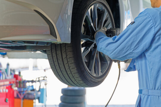 Mechanic using an impact wrench on a car wheel in an auto repair shop during maintenance work
