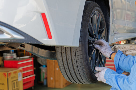 Close up of a mechanic handling lug nuts on a car wheel during maintenance in an auto repair shop