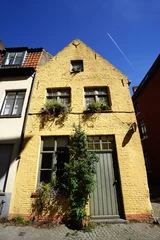 Altes Haus in Beige und Naturfarben mit Holztür, Sprossenfenster und begrünter Fassade bei Sonnenschein in der Altstadt der Unesco Welterebestadt Brügge in Westflandern in Belgien © Martin Debus