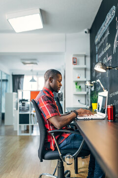 Focused programmer working on laptop in modern office