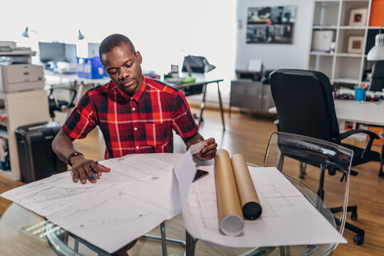 Designer reviewing blueprint plans at modern studio desk