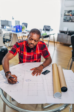 Young engineer drafting blueprint plans in modern office